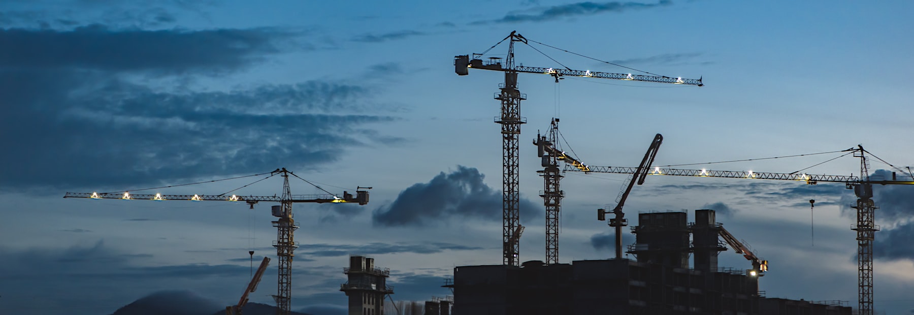 Grues de chantier au crépuscule (illustration générique du secteur BTP)