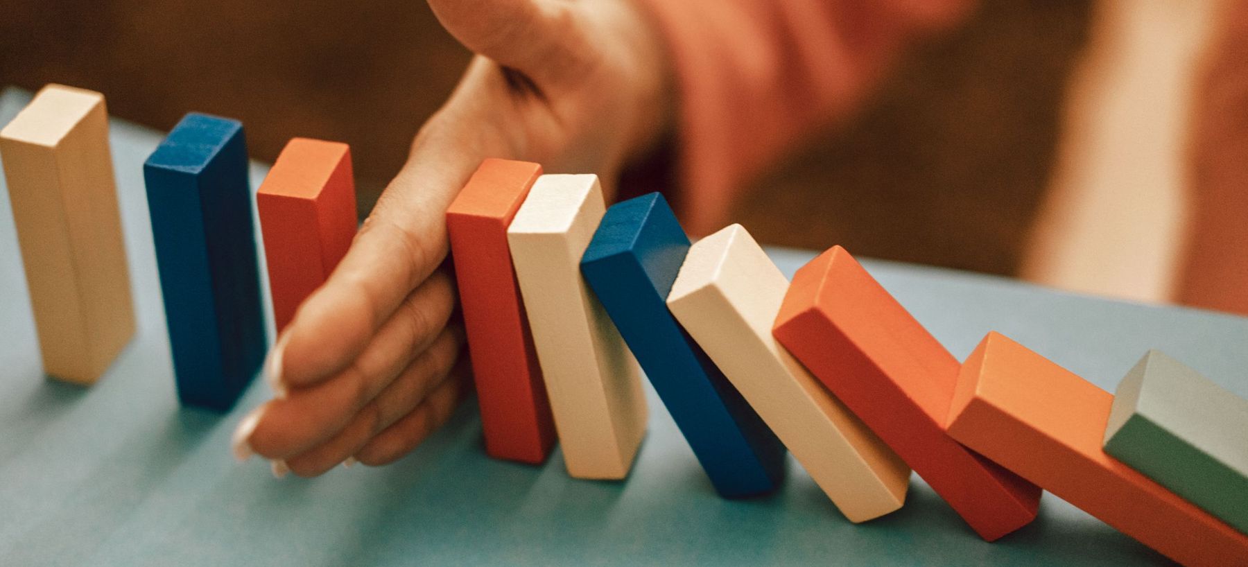 Main interrompant une chaîne de dominos qui s'effondre