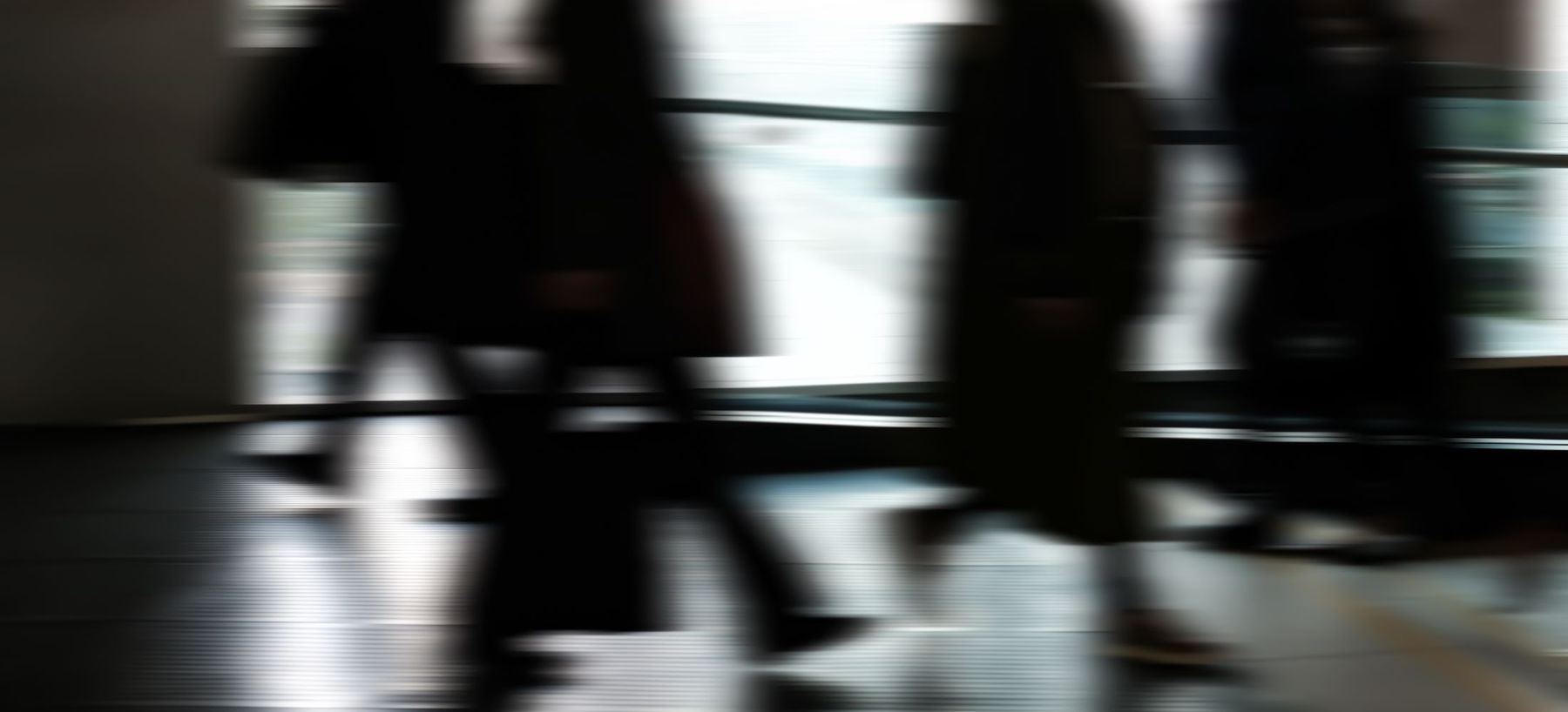 Silhouettes floues de collaborateurs pressés dans un couloir